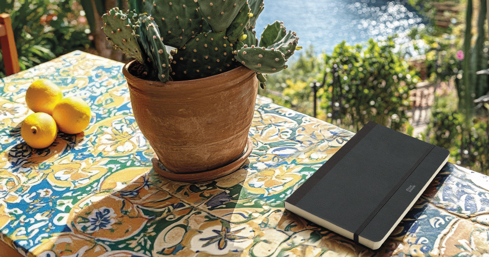 A notebook in a table nex to a cactus